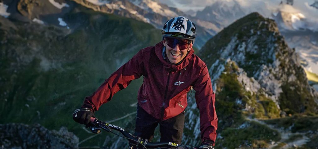 Hombre sonriendo andando por el monte con la bicicleta